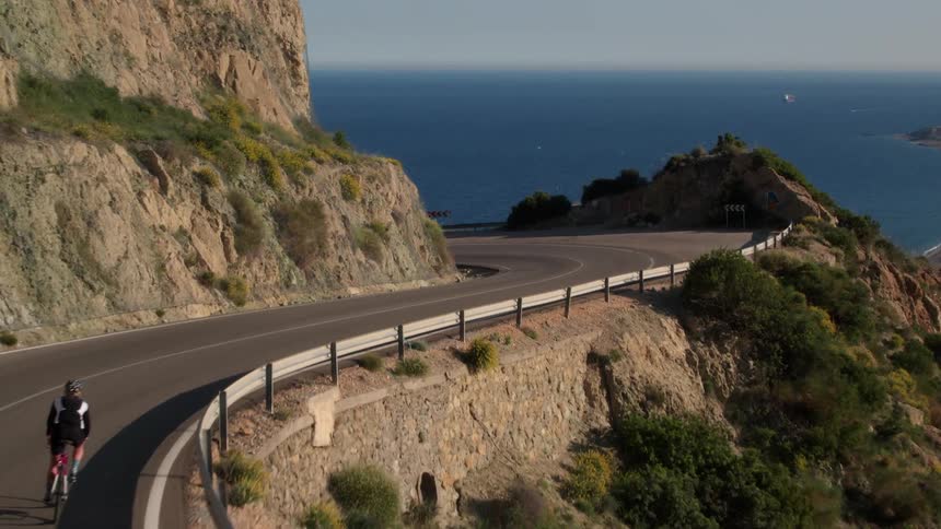 A man is riding his bicycle along the empty road in the south of Spain