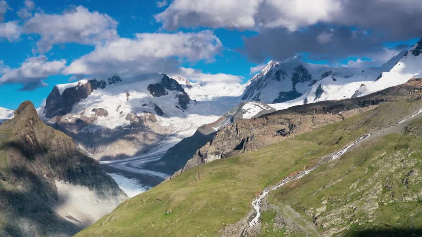 Clouds and shadows move over the snowy mountain peaks