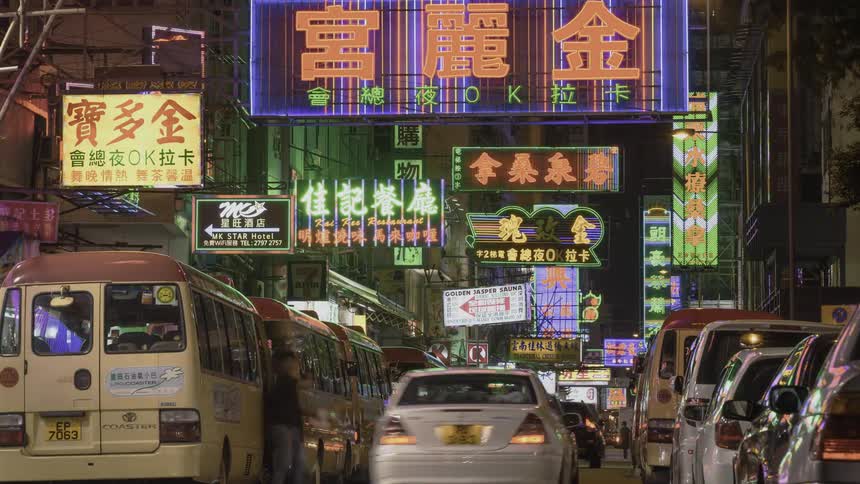 Vehicles are navigating a narrow city street in an asian city at night