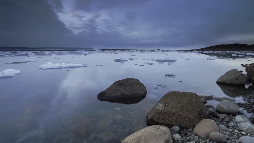 The ice floats along the water at sunset