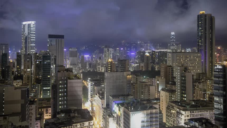 Clouds and lightning passing over a brightly lit city