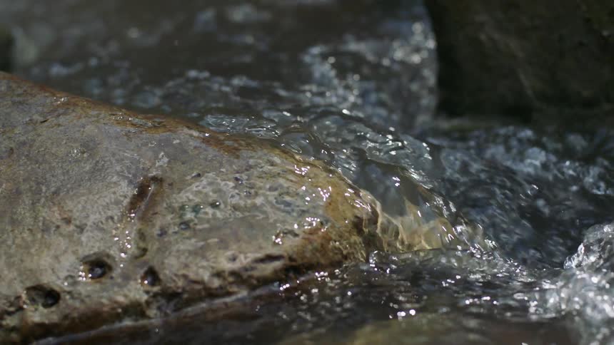 The water rushes over the rocks on a sunny day