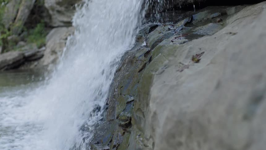A waterfall is falling down and smacking against the rocks