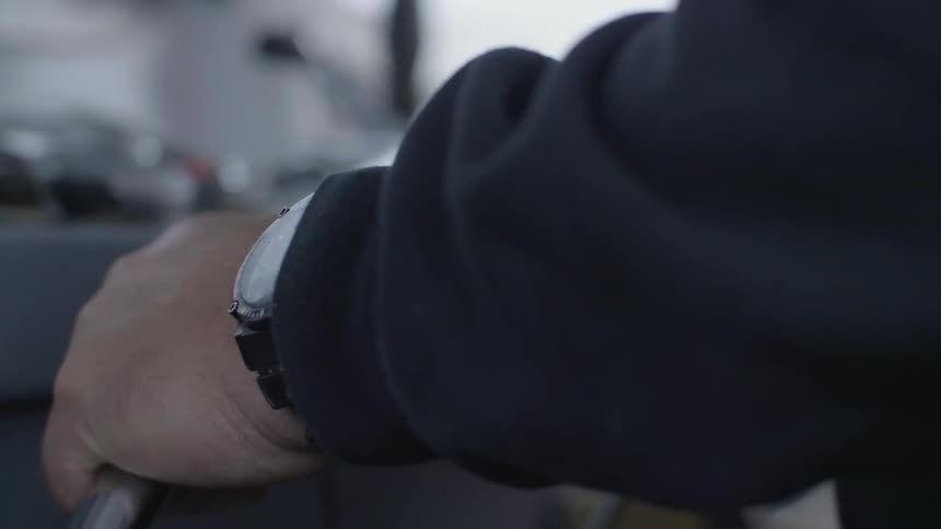 A person has his hand on the steering wheel of a boat