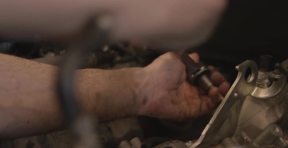 A man uses a ratchet to perform a repair