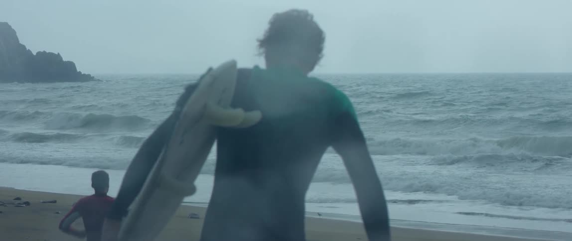 Some people are carrying surfboards towards the ocean