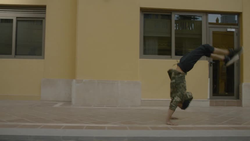 A young man is back flipping down the sidewalk