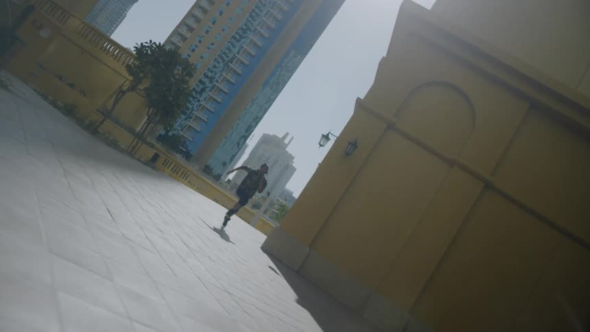 A young man is running down the sidewalk and past the camera