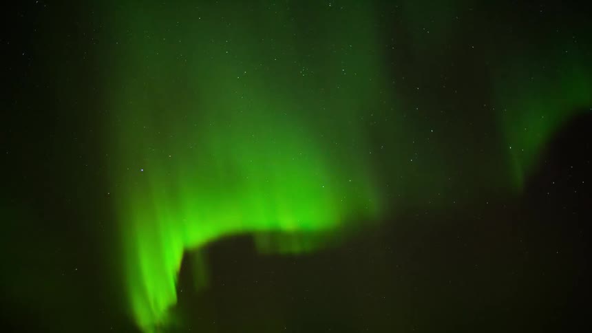 The northern lights create green swirls in the sky
