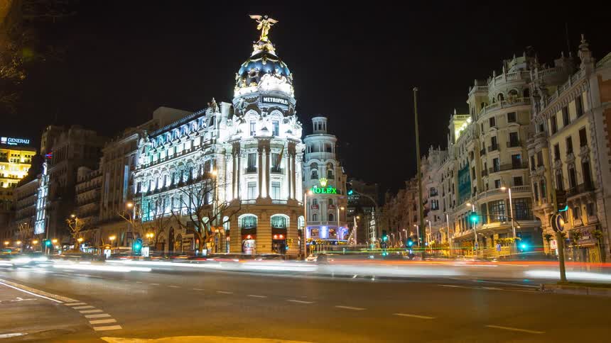 Traffic flows through a busy urban intersection at Gran Via at night
