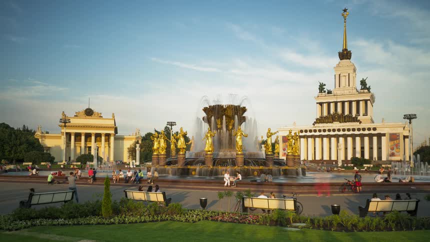 People walking around a fountain near a palace