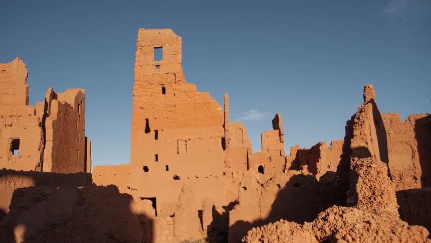 A shadow is cast over stone ruins at sunset