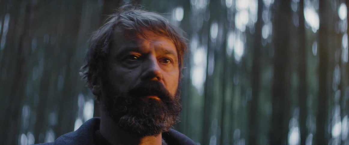 Light from a fire shines on a man's face then dims
