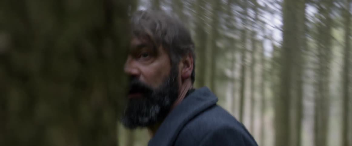 A man in a forest whips around looking behind and above