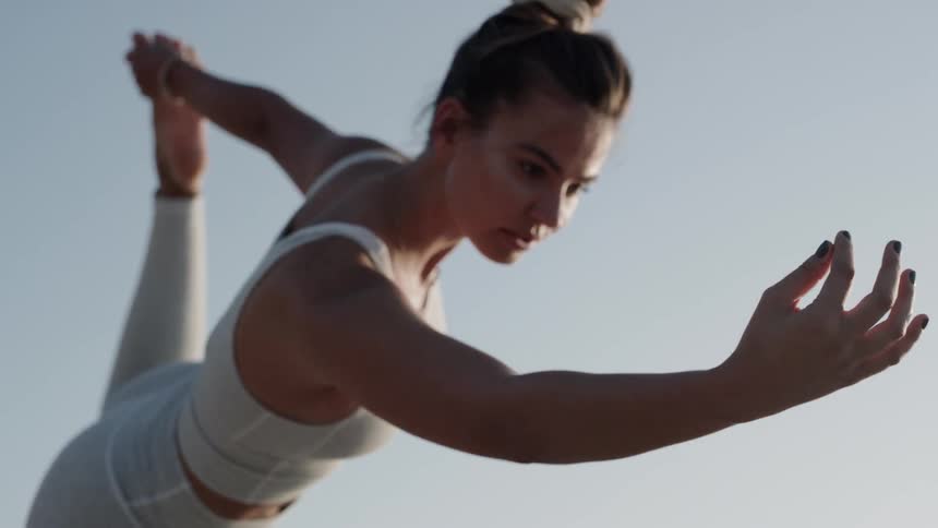 A woman reaches outward while stretching outside