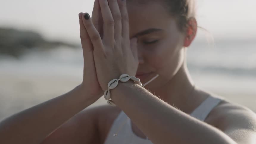 Woman practices yoga on the beach on a sunny day