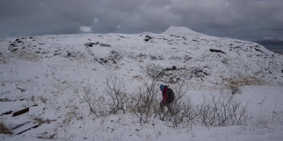 Someone is hiking through the snow towards a large hill