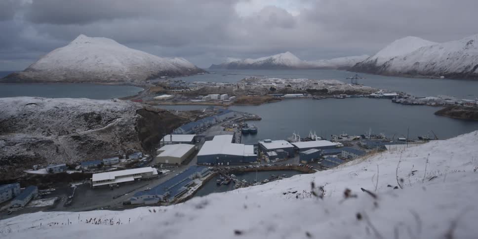 Snowy mountains surround a village on the sea