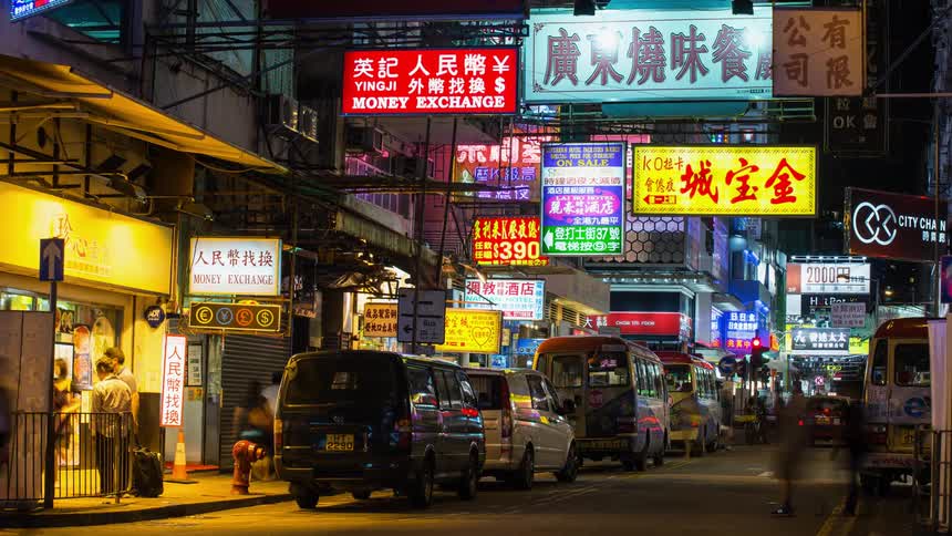 The busy city has many bright signs above the people