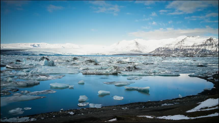 Blocks of ice float on the ocean surface as clouds pass over