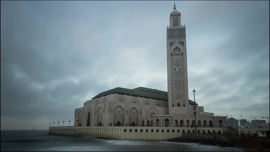 Clouds pass over the water and a tower building