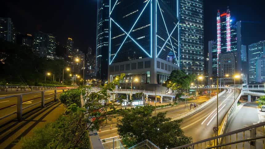 Traffic is flowing on a freeway in an urban area at night