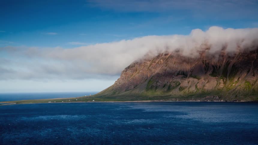 The clouds move along the top of the mountain