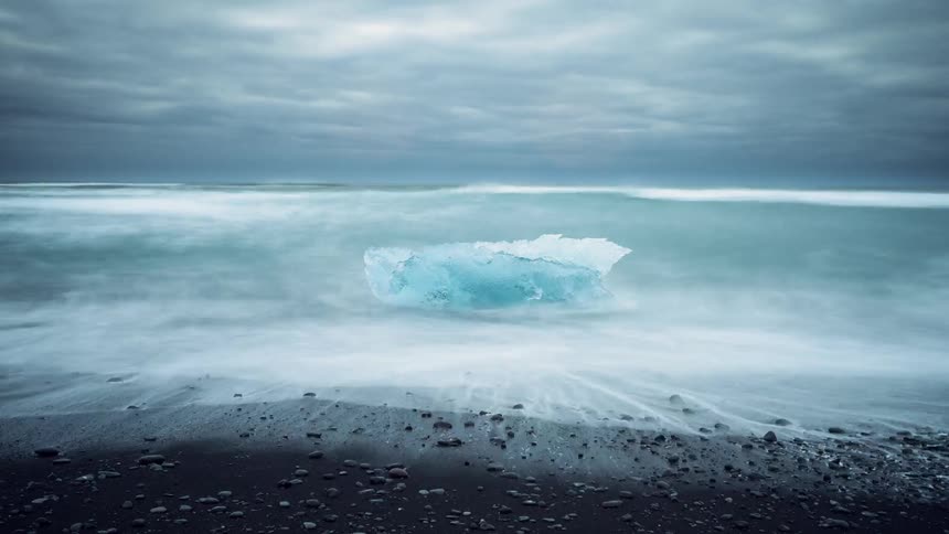 Ocean water comes to shore past a chunk of ice