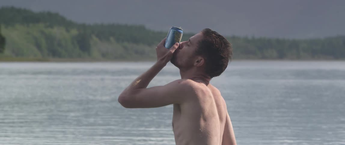 A man shotguns a beer at the beach