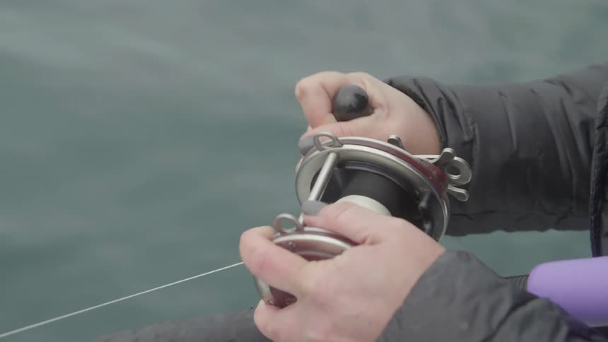 A person fishing reels in the line
