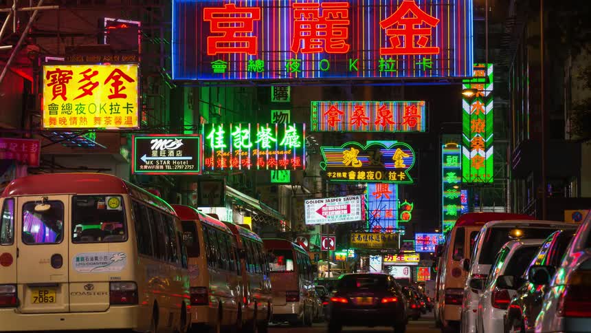 Cars and people travel along the busy brightly lit city