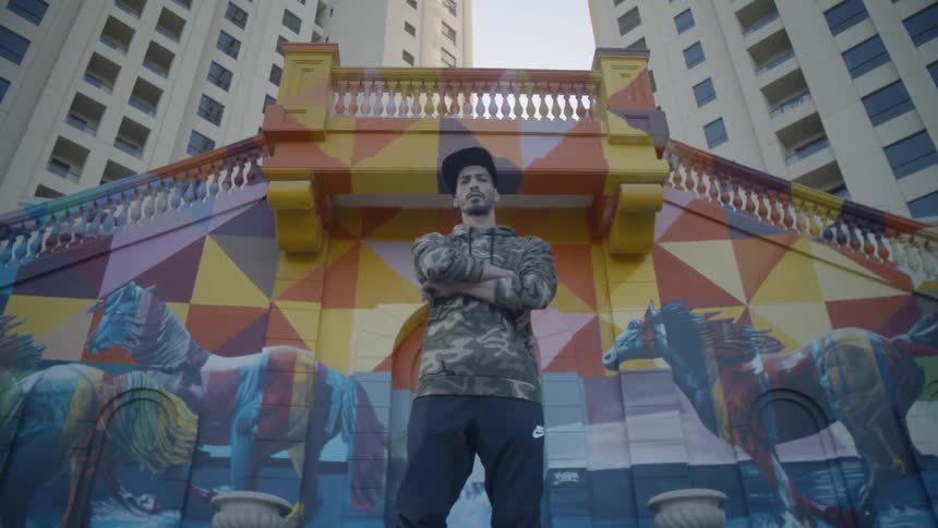A man stands atop a set of stairs in the city and crosses his arms