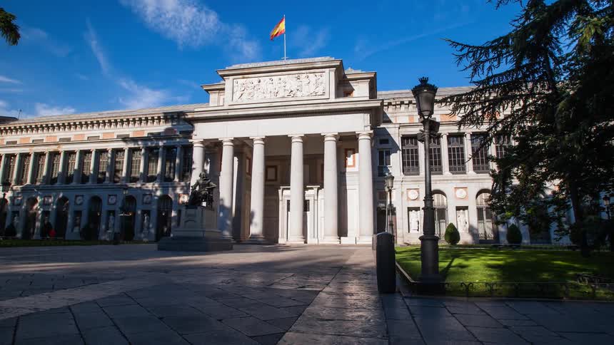 Tourists and pedestrians are walking past Museo del Prado during the day
