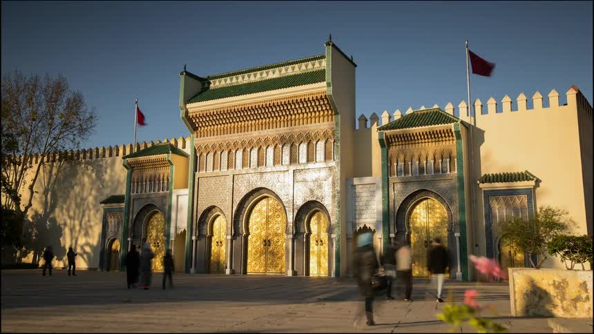 People walk through the square in front of an oriental palace with gold doors