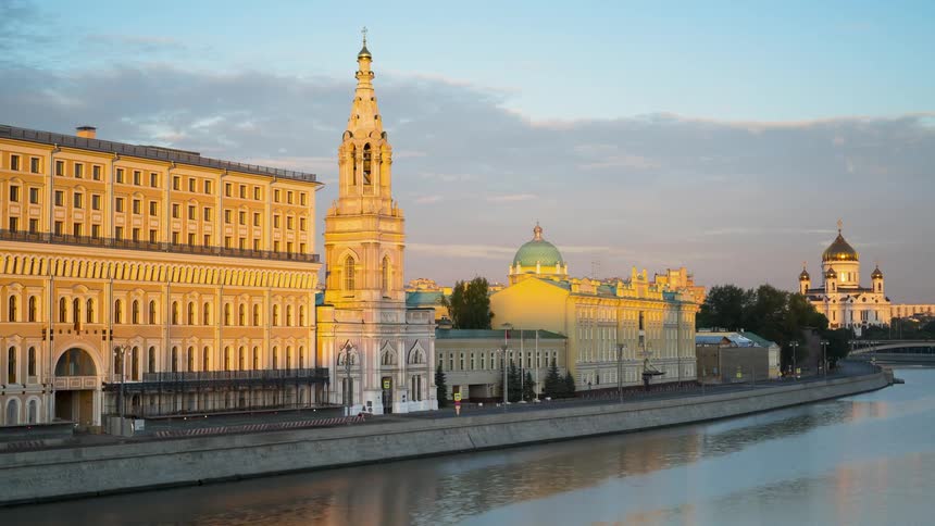 River flowing by city buildings at sunset in Moscow