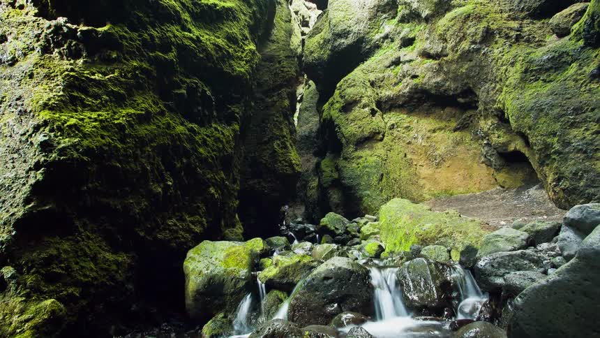 Waterfall is flowing between cracks in a rock
