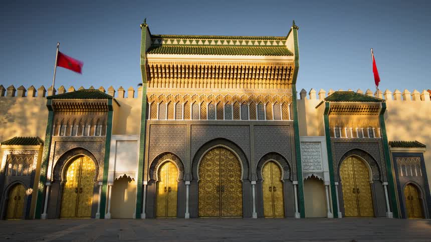 Time lapse of the outside of an Arab palace with golden doors and red flags on top