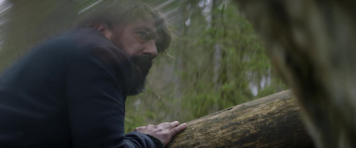 A man looks around cautiously in the woods