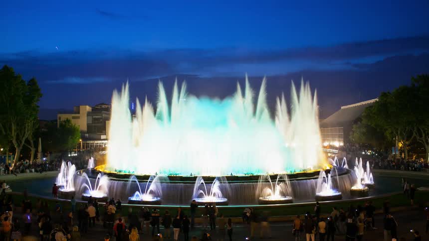 A multicolored fountain sprays water in the evening