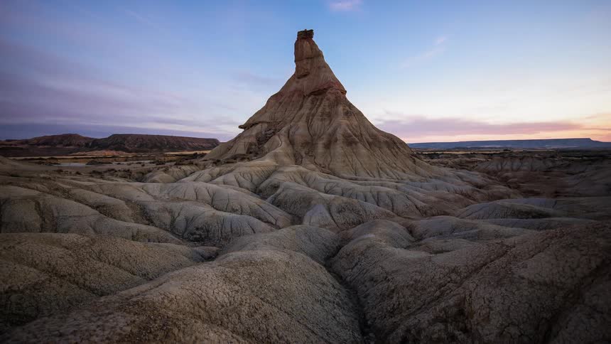 Clouds pass over a rock formation in the wilderness at sunrise