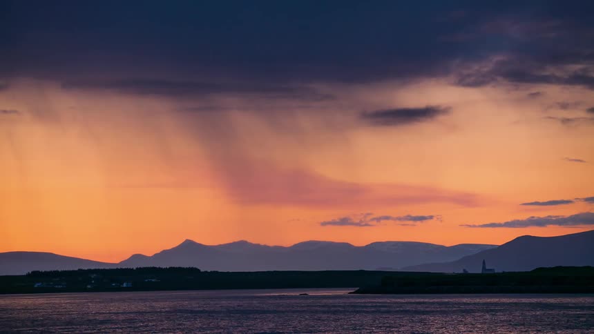 It rains over a mountain lake at sunset