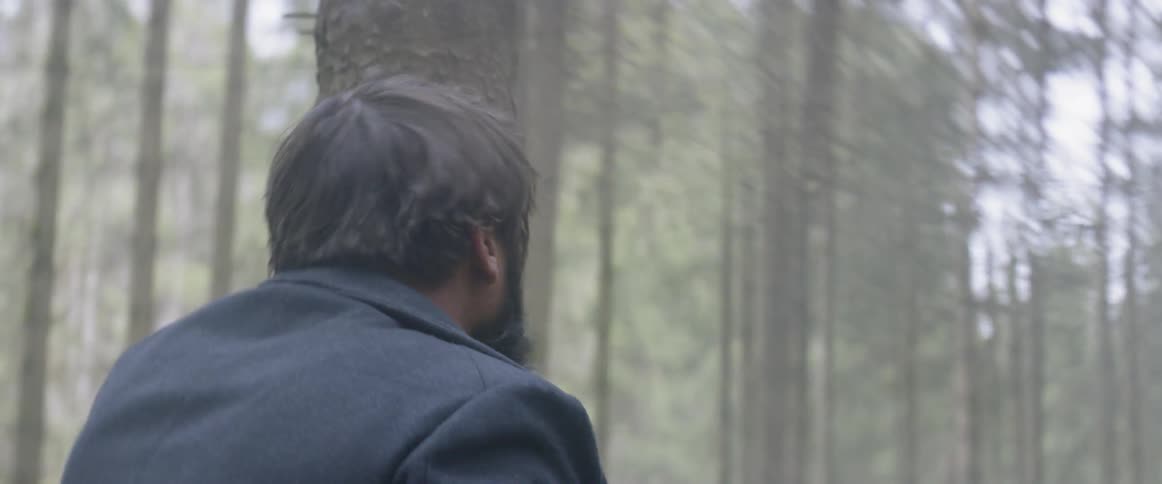 A man looks to be frightened by something in the woods