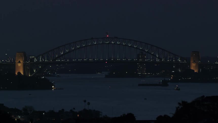 Cars travel across the harbour bridge at night