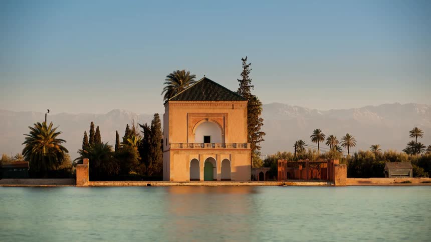 Wind blows the palm trees around a building on the water