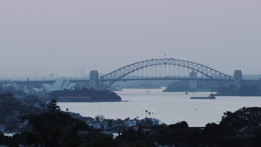 A city bridge spans a river at sunset