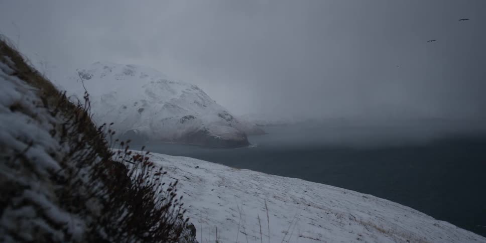 A lake is surrounded by snowy mountains