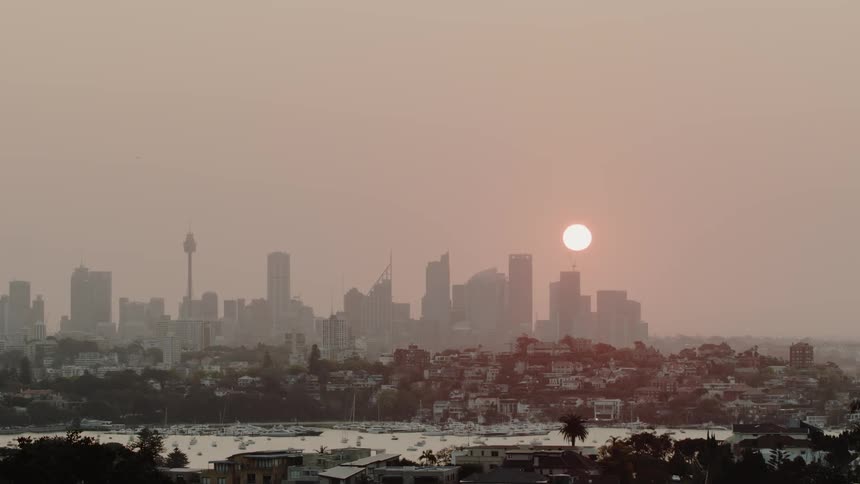 The sun sets behind skyscrapers