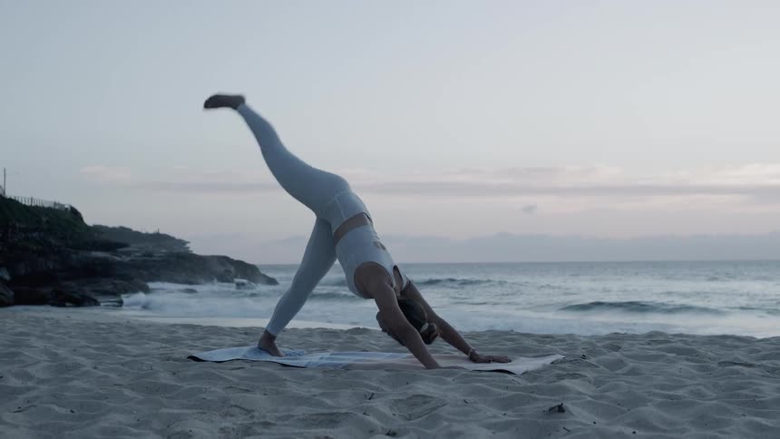 A woman is doing yoga on the beach