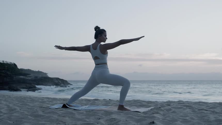 A woman does yoga on the beach