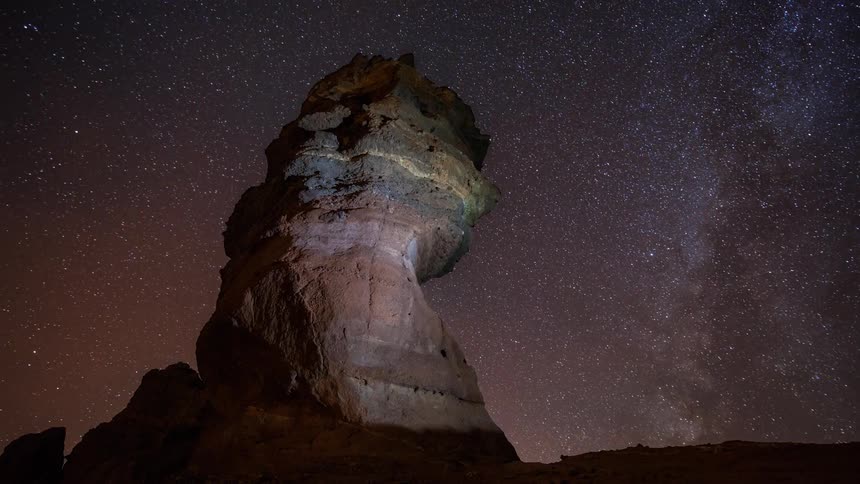 Stars illuminate the sky above a rock formation